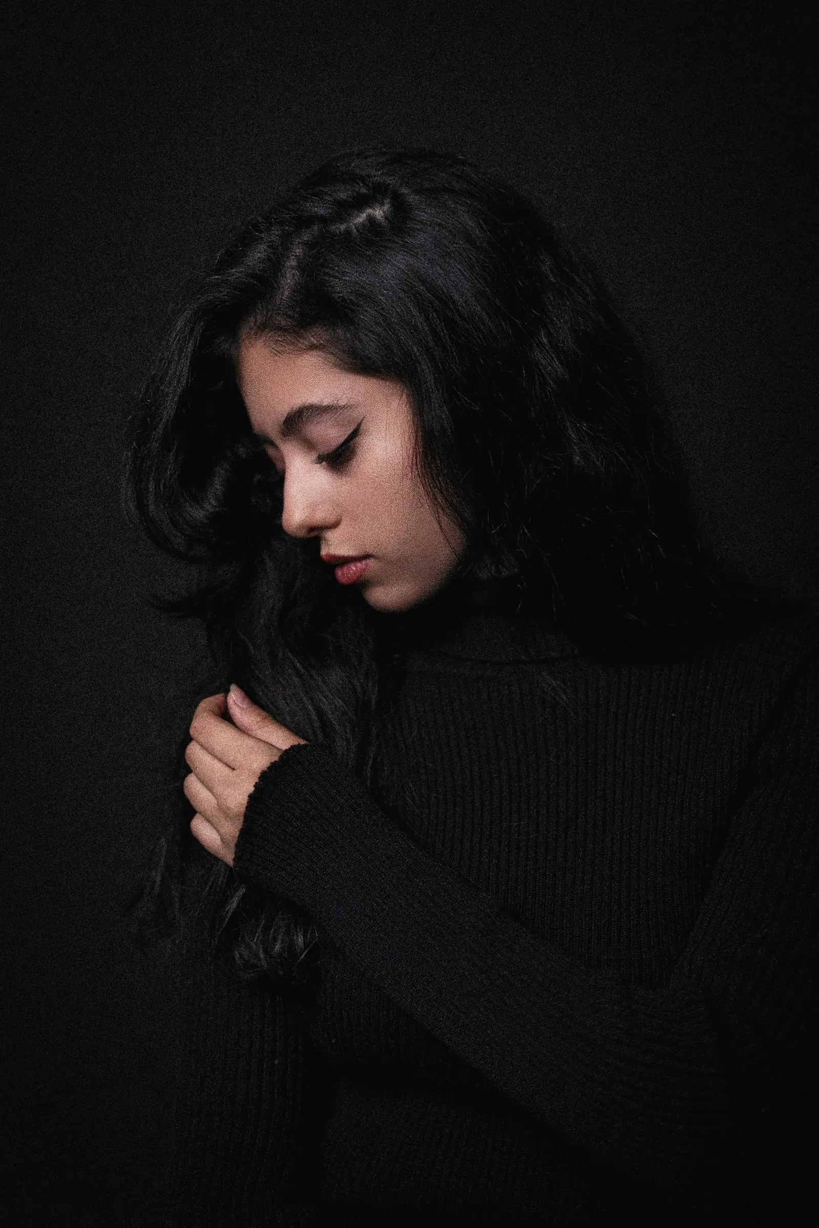 Woman with long dark hair, eyes lowered